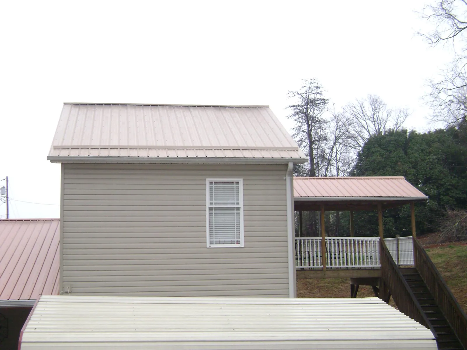 Tan metal roofs on a two story addition and attached porch, from a Roof Replacement job in Wysox