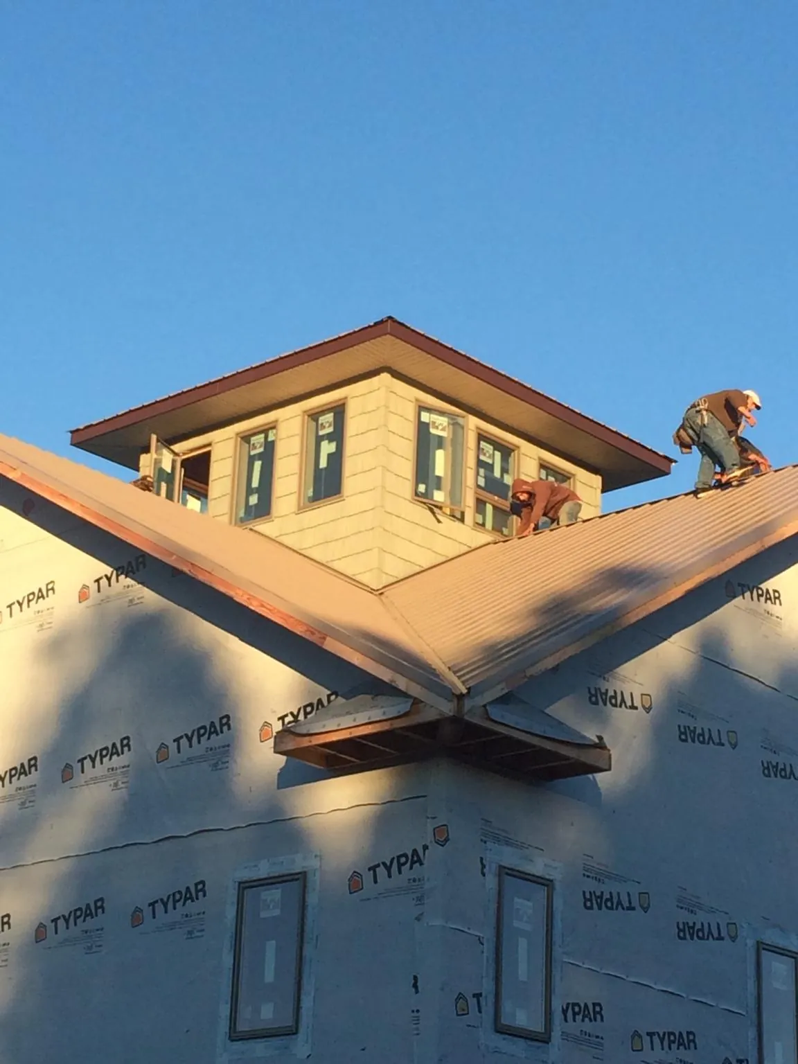 Roofers working around a rooftop cupola on a new metal roof at sunset — Roof Waterproofing in Wysox by Roofing Brothers